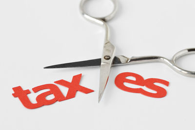 Close-up of taxes text with scissors over white background