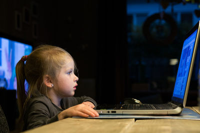 Close-up of girl using laptop at night
