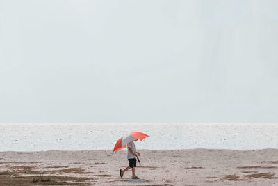 Man with umbrella walking at sea shore