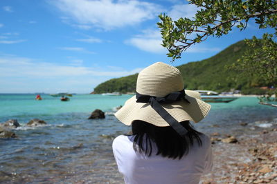 Rear view of woman on beach against sky