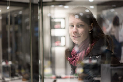 Portrait of woman reflecting on store window at night