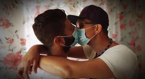 Midsection of young woman with sunglasses on bed at home