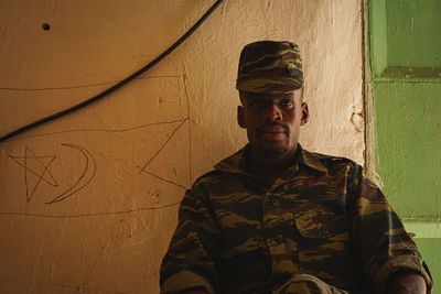 Portrait of young man standing against wall