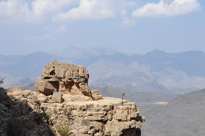 Rock formations on landscape against cloudy sky