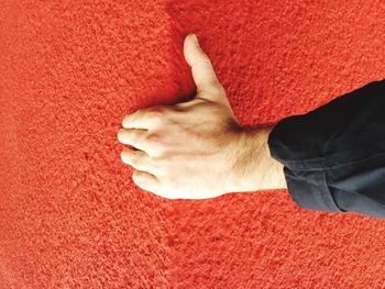 Cropped image of man hand showing thumbs up on red wall