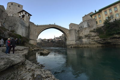 Mostar bridge. people at historic building against clear sky