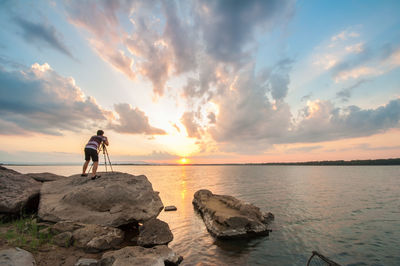 Scenic view of rocks on beach against sky during sunset