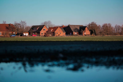 Houses on field by buildings against sky