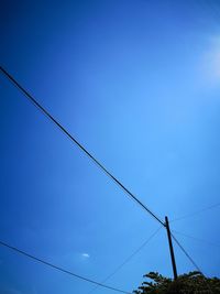 Low angle view of power lines against clear blue sky