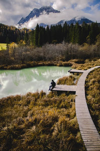 Young man sitting by lake during autumn