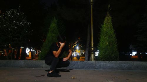 Man sitting in illuminated city at night