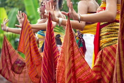 Low section of woman dancing on street with traditional textiles from bali, indonesia.