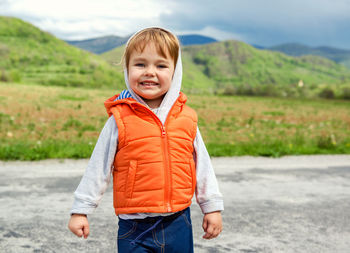 Portrait of smiling boy standing on mountain against sky