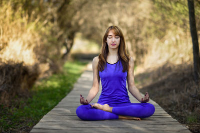 Beautiful mid adult woman doing yoga on boardwalk