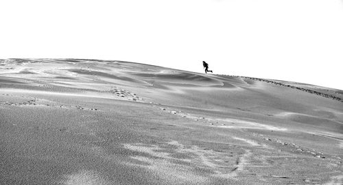 Silhouette man on sand dune against clear sky
