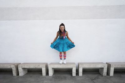 Portrait of woman standing on seat against wall