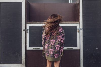 Rear view of woman standing against door