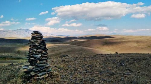 Stack of rocks on field against sky