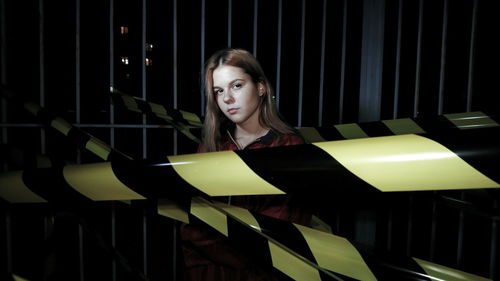 Portrait of woman standing by cordon tapes at night