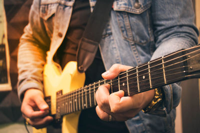 Midsection of man playing guitar