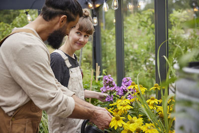 Side view of senior couple standing by plants