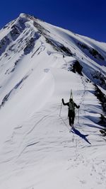 Rear view of man skiing on snowcapped mountain against sky