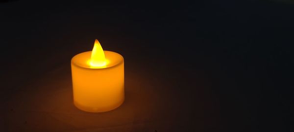 Close-up of lit candle in darkroom