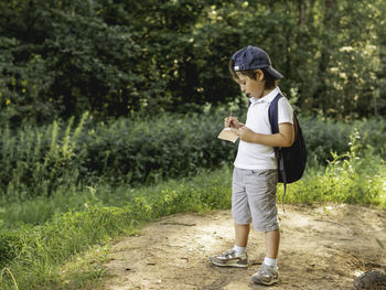 Mindful boy writes in notebook while walking in forest. exploring nature. summer recreation. 