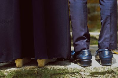 Low section of couple standing on retaining wall