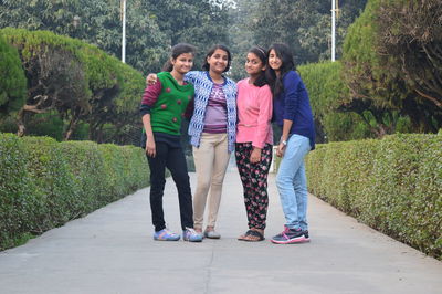 Full length portrait of happy friends standing on walkway