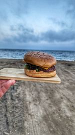 A hamburger on a wooden tablet by the ocean 