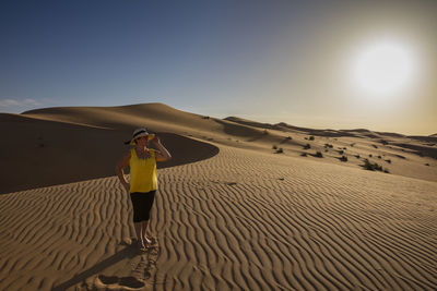 Senior woman standing at desert against clear sky