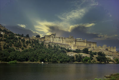 Scenic view of river by city against sky and amer fort of jaipur rajasthan 