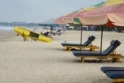 Lounge chairs and parasols on beach against sky