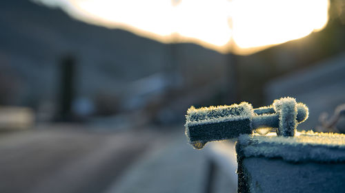 Close-up of frozen railing against sky during winter