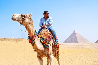 Full length of man standing on sand against clear sky