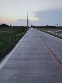 Empty road against sky during sunset