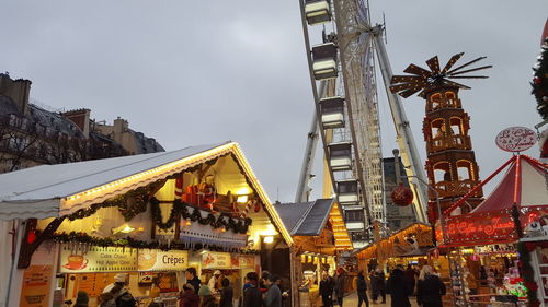 People at amusement park against sky in city