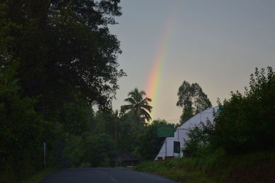 Rainbow over road by building against sky