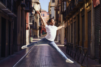 Full length portrait of young man dancing at street
