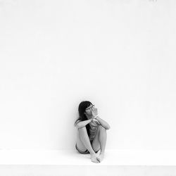 Woman sitting against white background