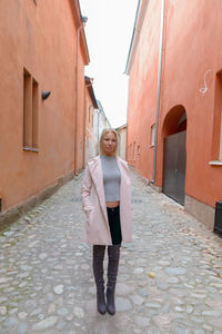 Full length woman standing on footpath amidst buildings