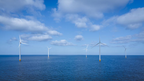 Wind turbines in sea against sky