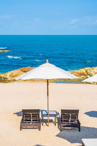 Chairs on beach against sky