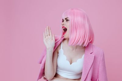 Portrait of young woman against pink background