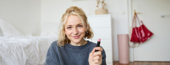 Portrait of smiling young woman using mobile phone while standing at home