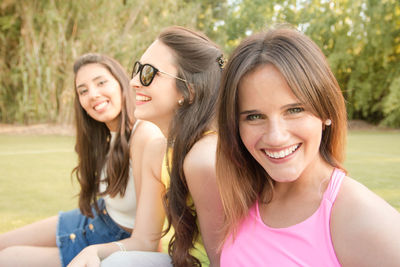 Portrait of smiling young woman with friends in park