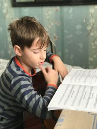 Boy reading musical note while holding guitar