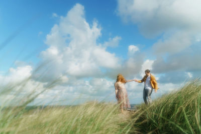 Couple standing on field against sky