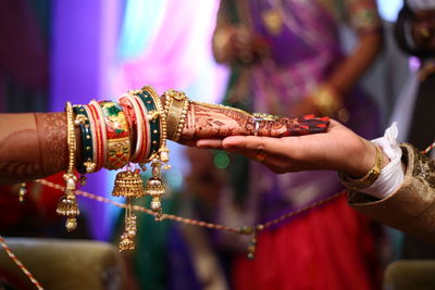 Cropped image of bride touching groom hand during wedding ceremony